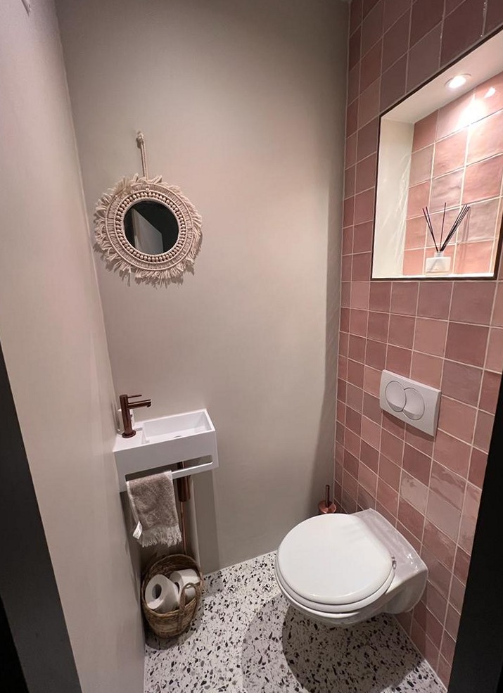 Kleine wc met roze tegelwand, nis en fonteintje