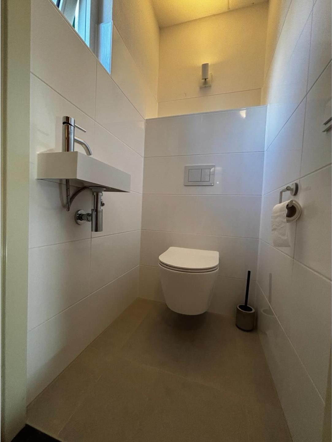 Witte betegelde wc met fonteintje en zwevend toilet in Sint Nicolaasga